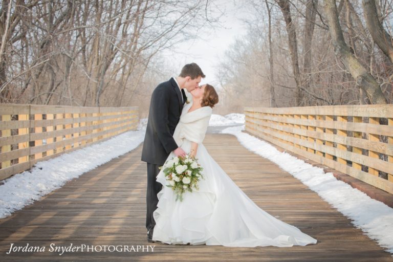 A bride and groom kissing on the bridge