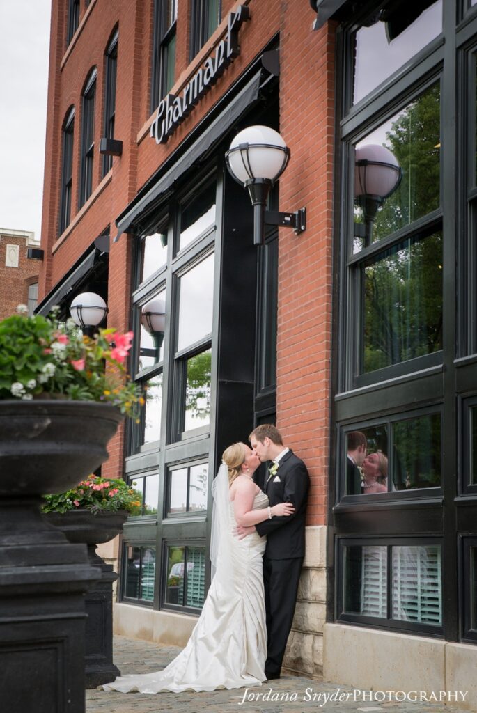 A bride and groom kissing in front of a building.