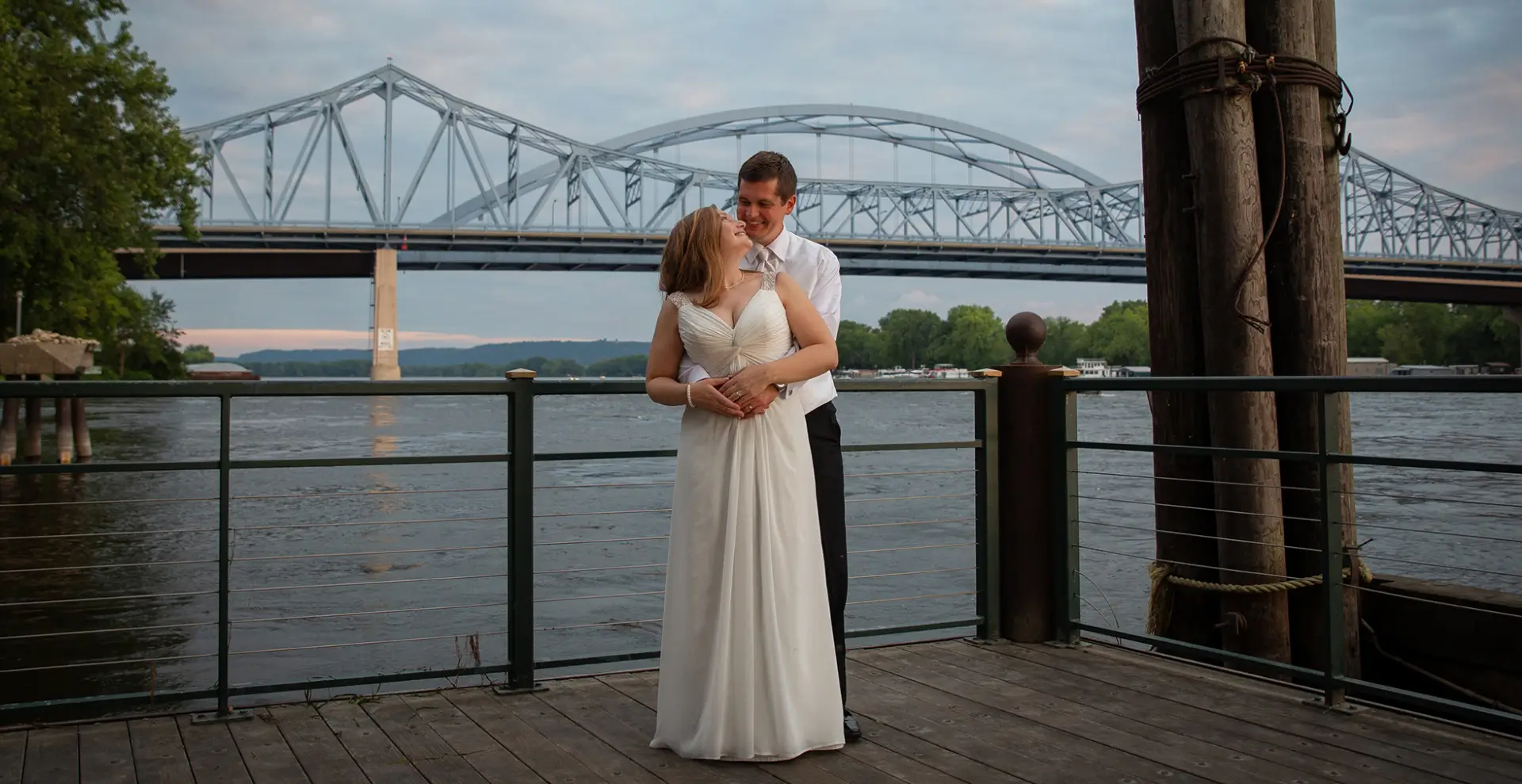 A man and woman standing on the pier near water.
