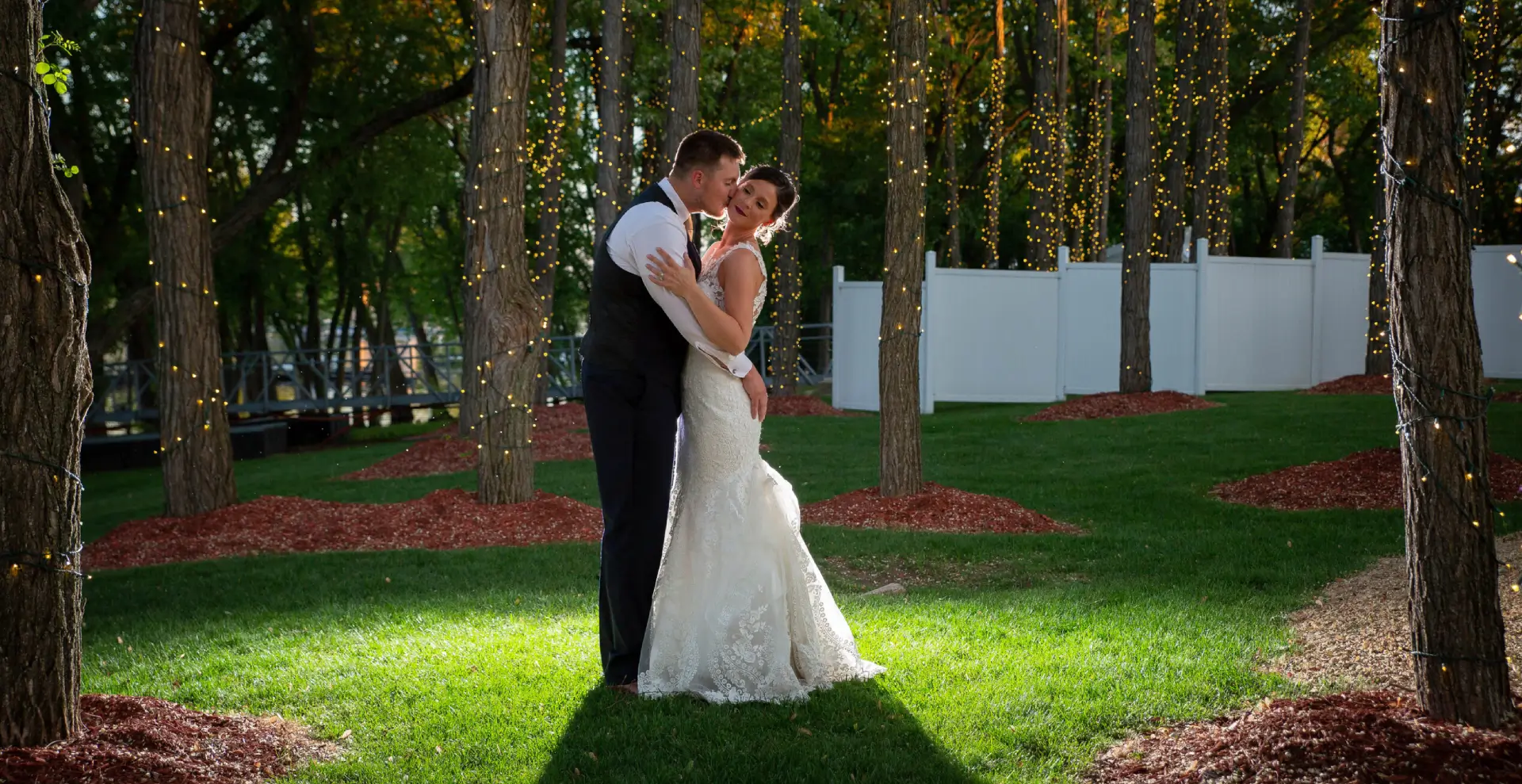 A bride and groom kissing in the grass.