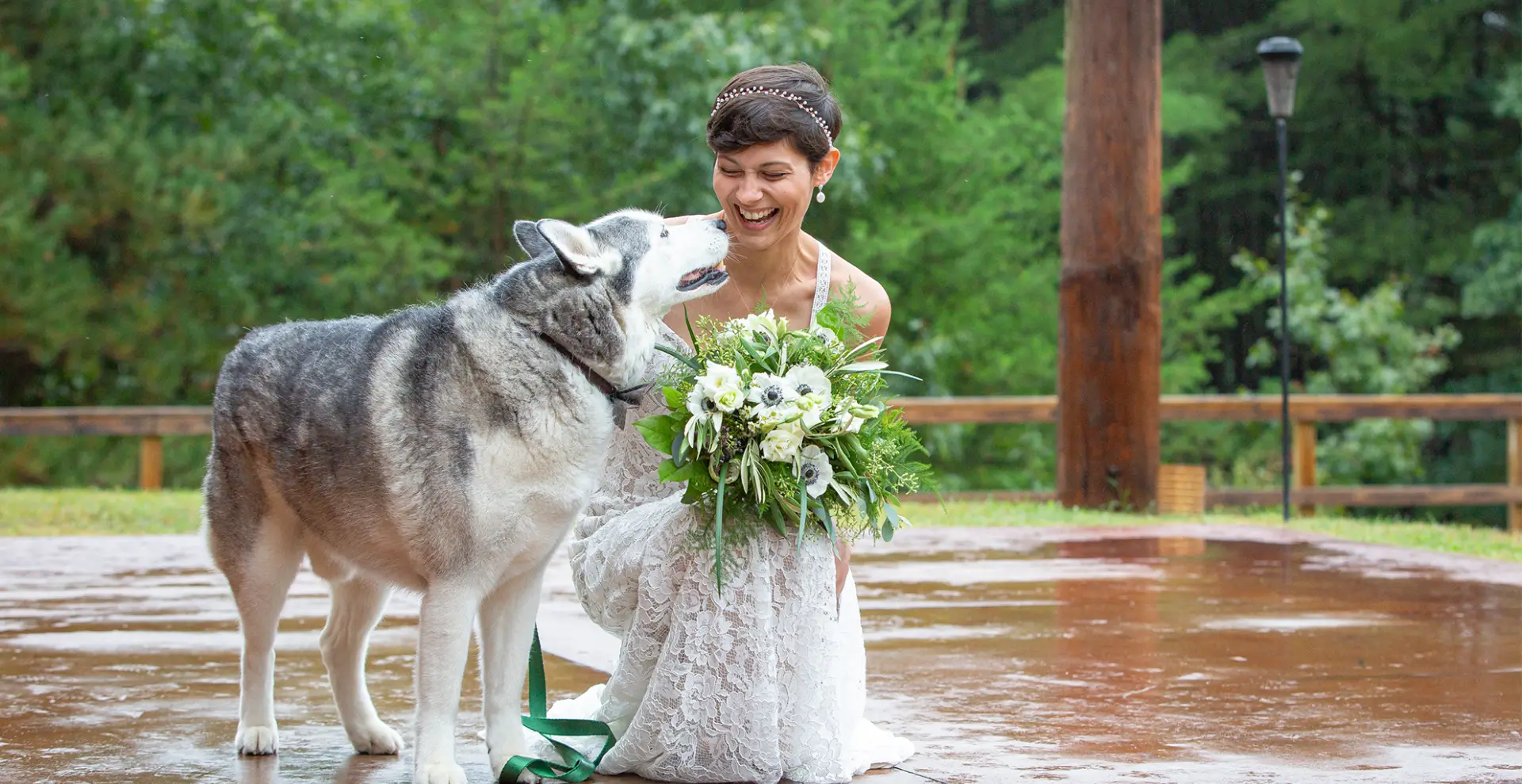 A woman in white dress standing next to a dog.