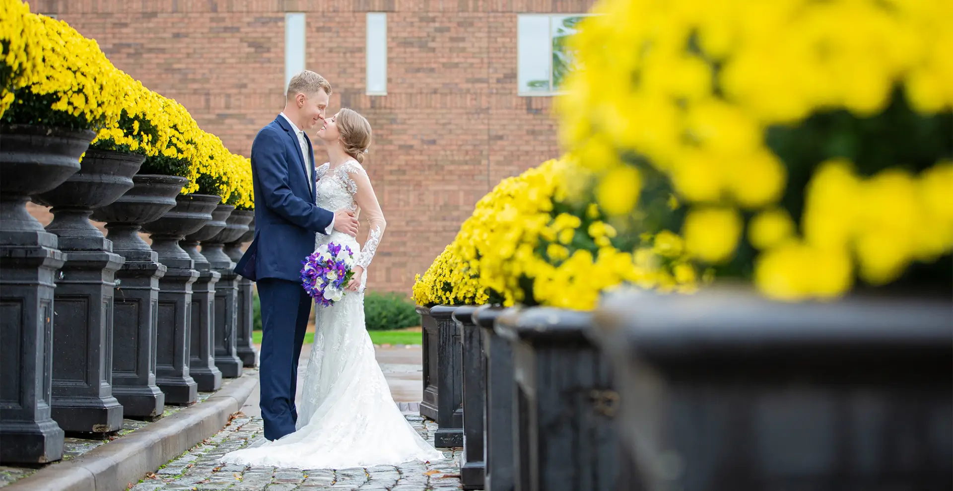 A bride and groom kissing in front of some flowers.