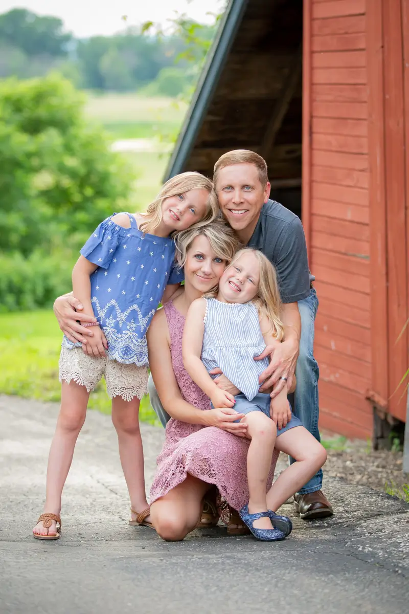 A family posing for a picture in front of a barn.