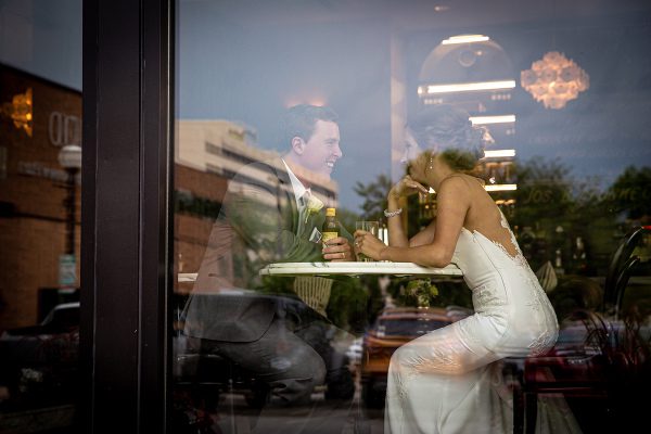 A woman in white dress sitting at table with drink.