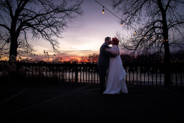 A couple is kissing in front of the sunset.