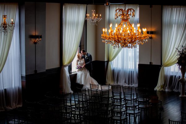 A bride and groom in front of a chandelier.