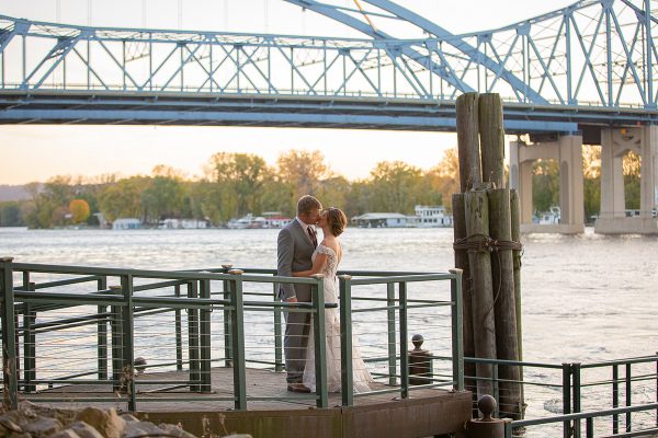 A couple is standing on the dock of a pier.
