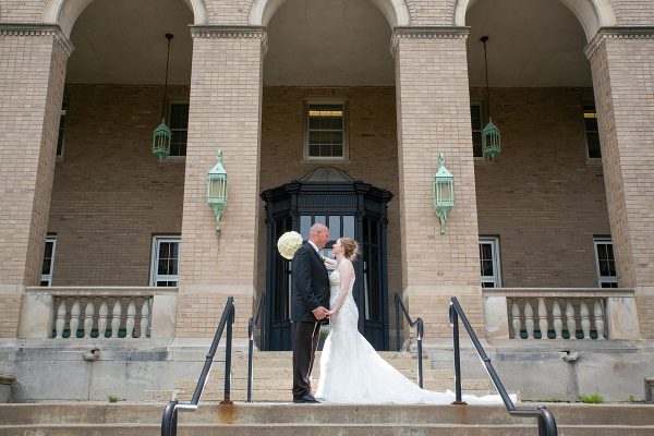 A bride and groom kissing on the steps of their wedding.