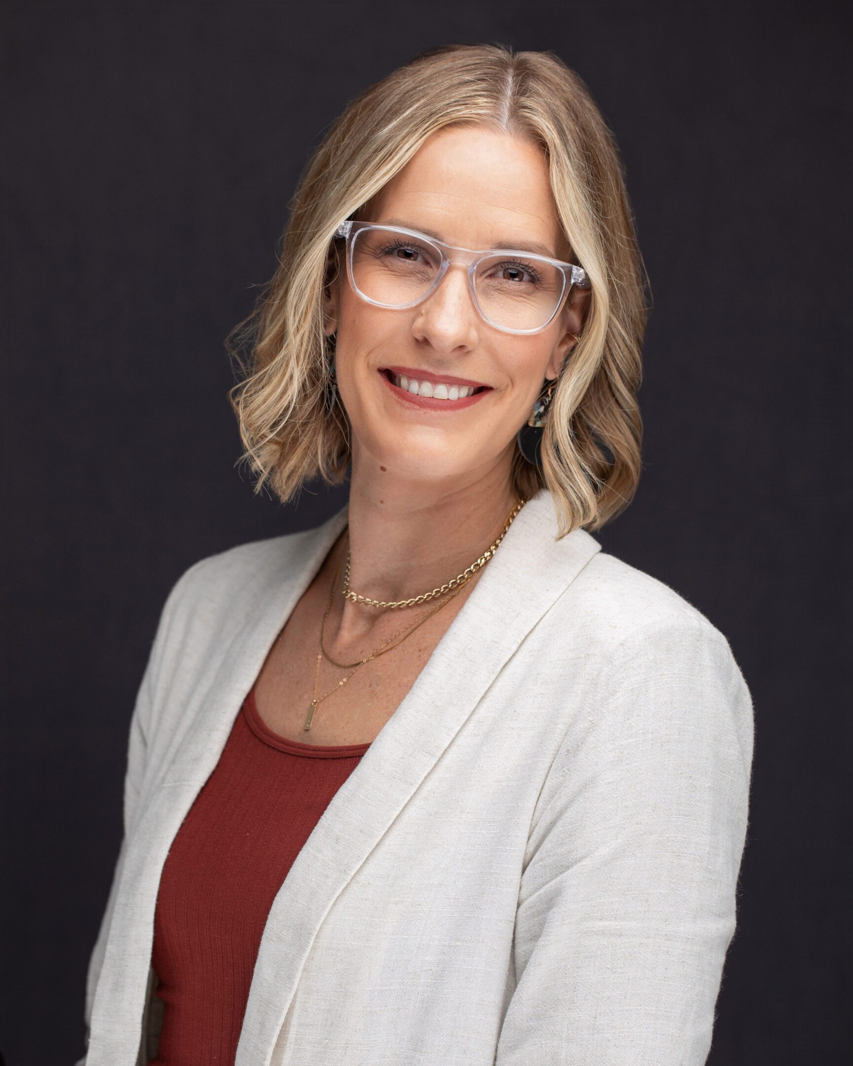 Smiling woman in blazer wearing clear glasses