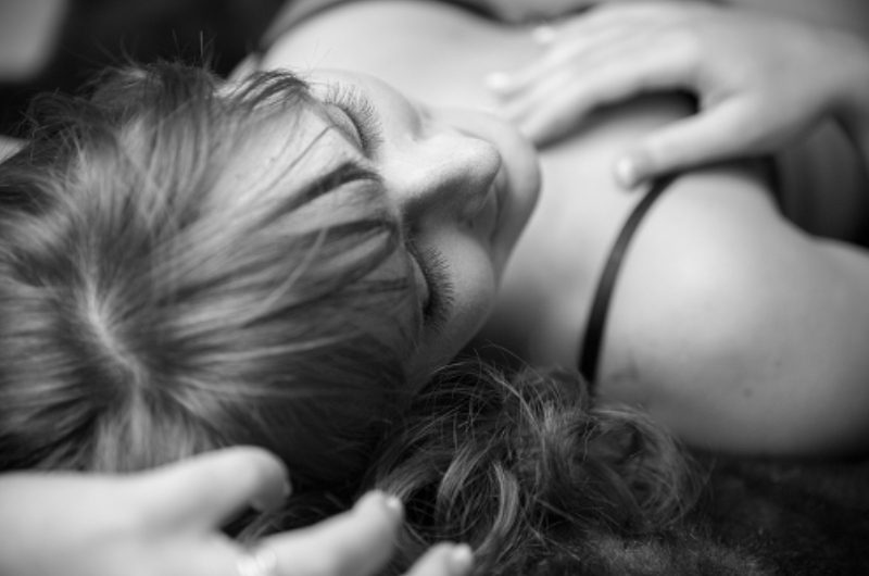 A woman laying on the ground with her hands in her hair.
