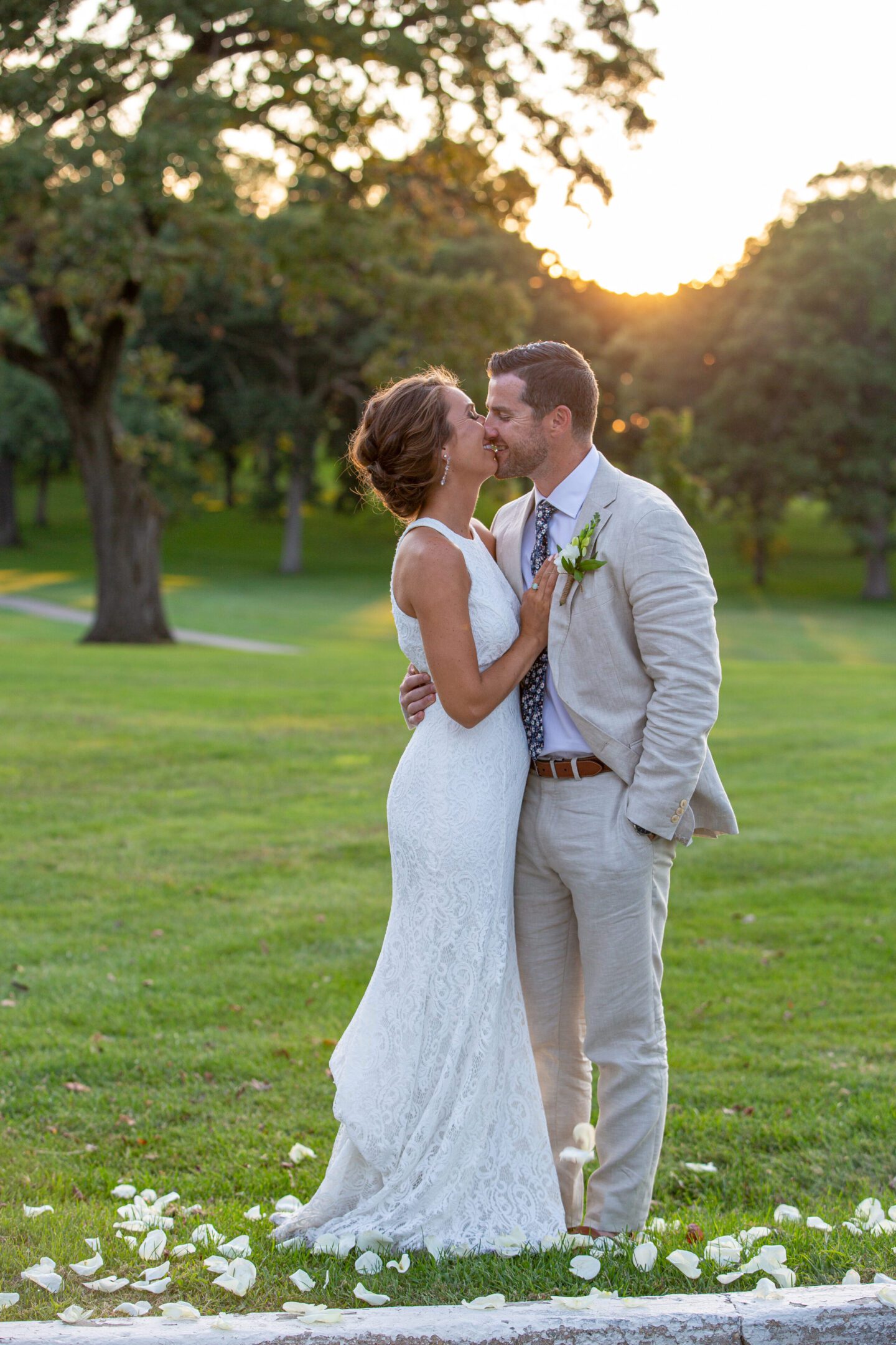 Newlyweds kissing in park at sunset