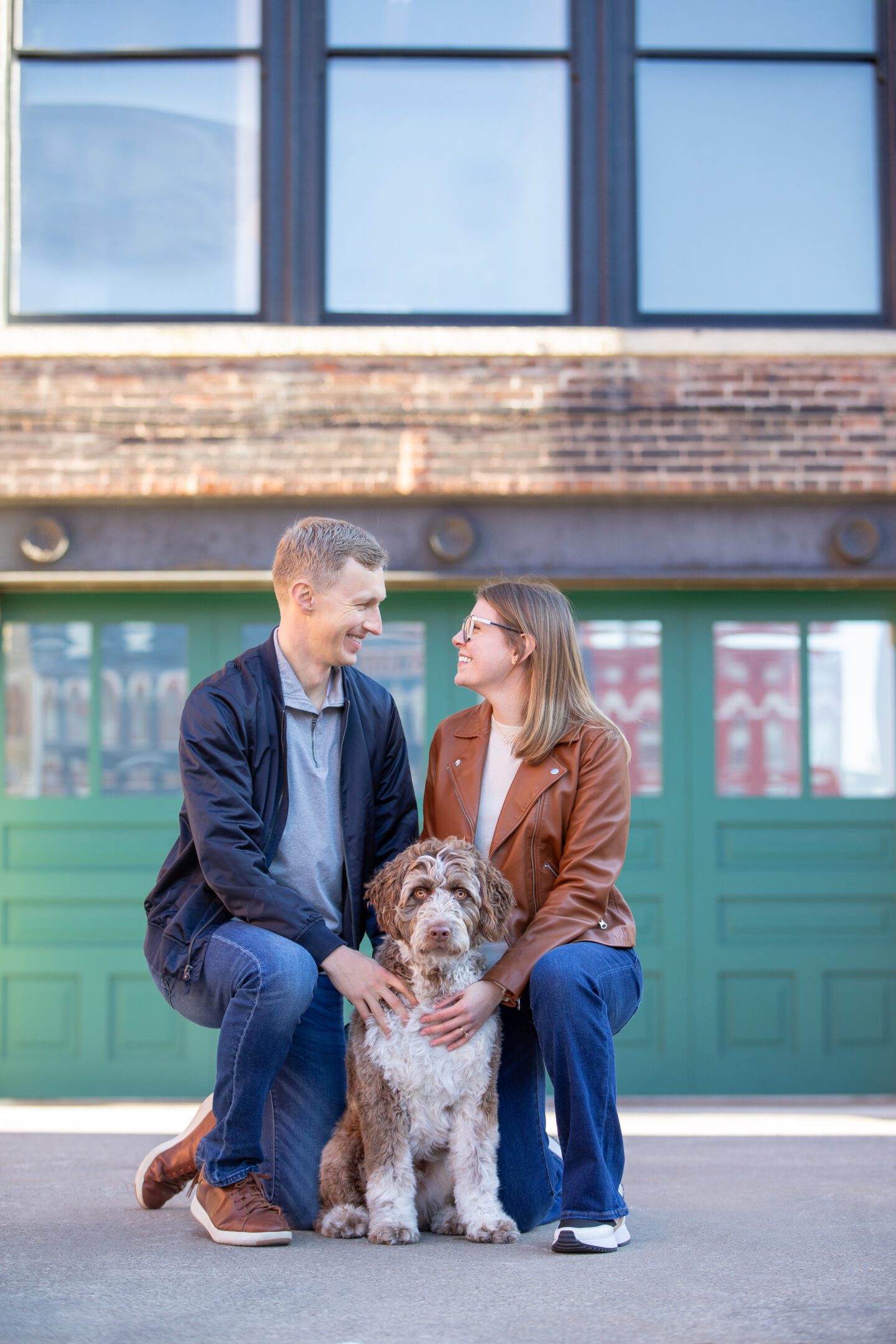 Smiling couple kneeling with dog outdoors