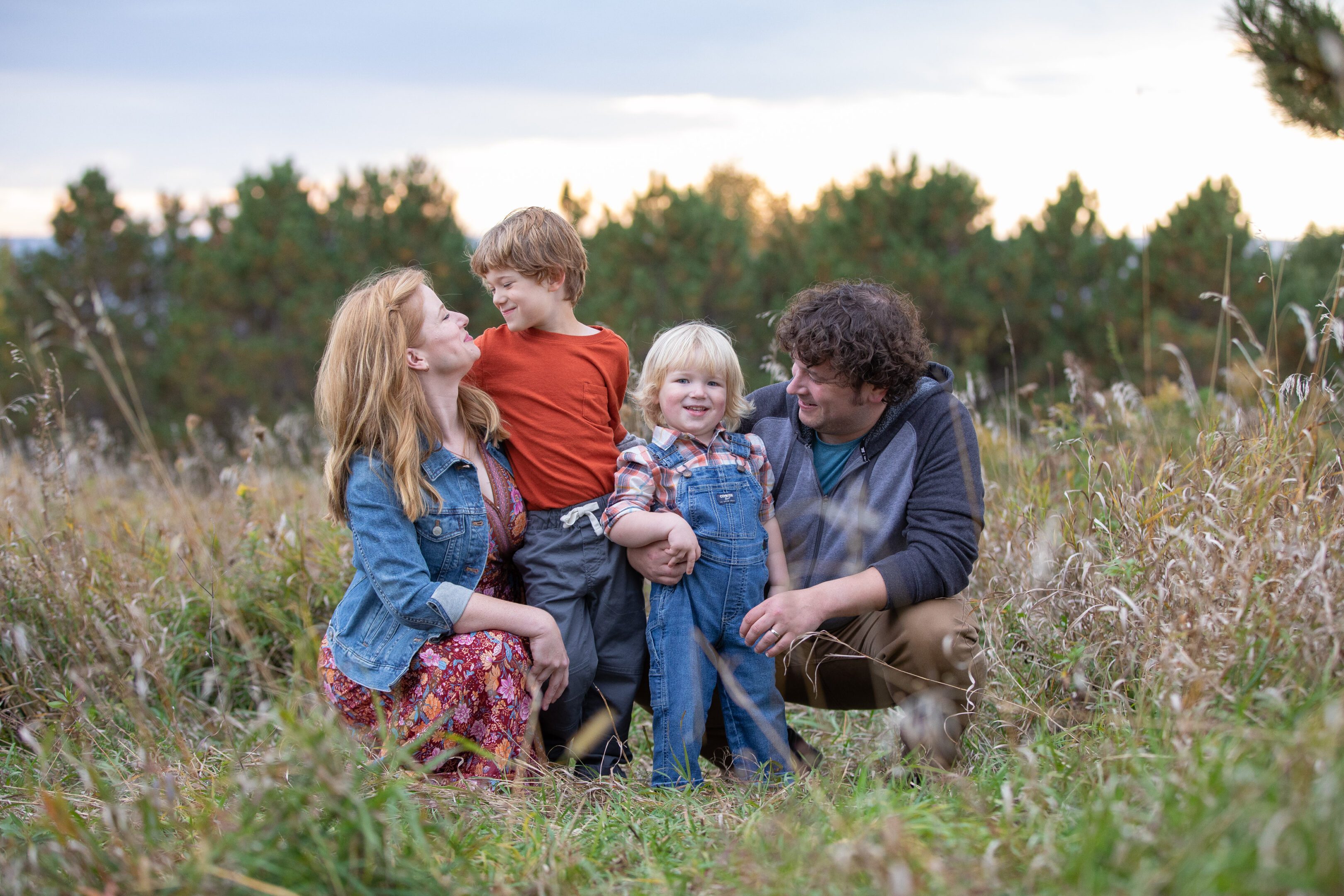 Smiling family of four in grassy meadow