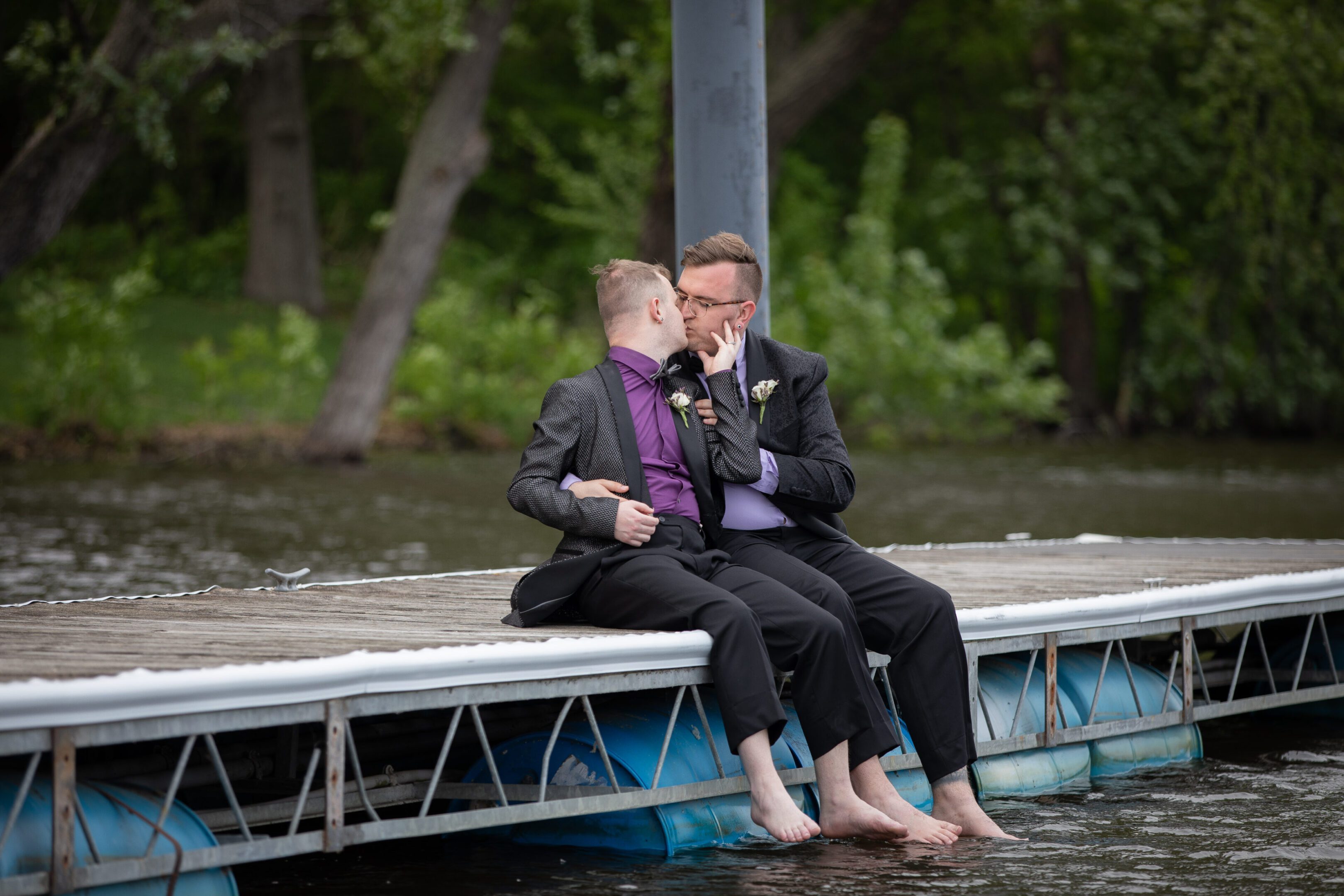 Two men in suits kissing on dock