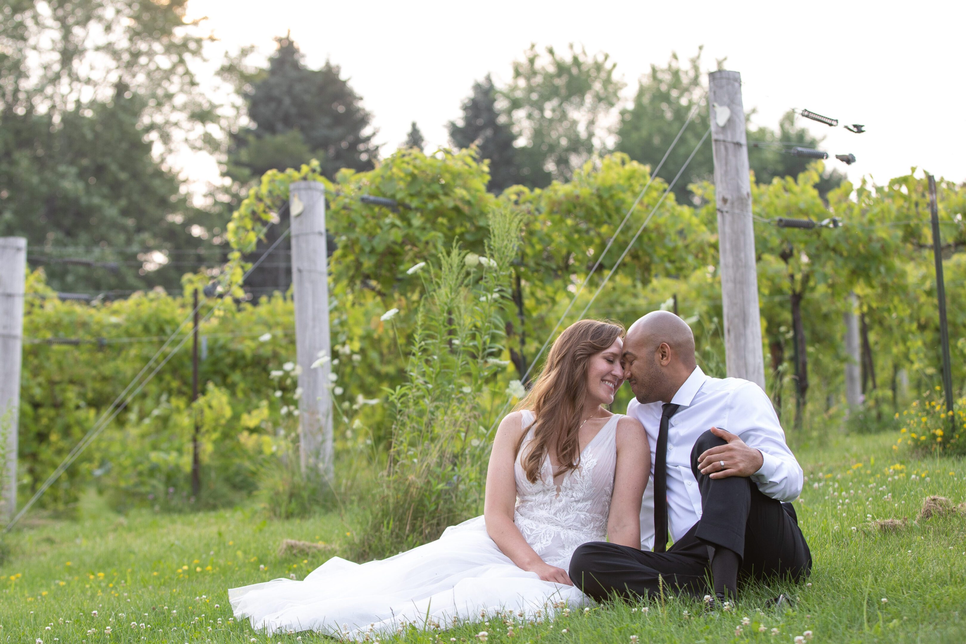 Bride and groom sitting in vineyard embracing