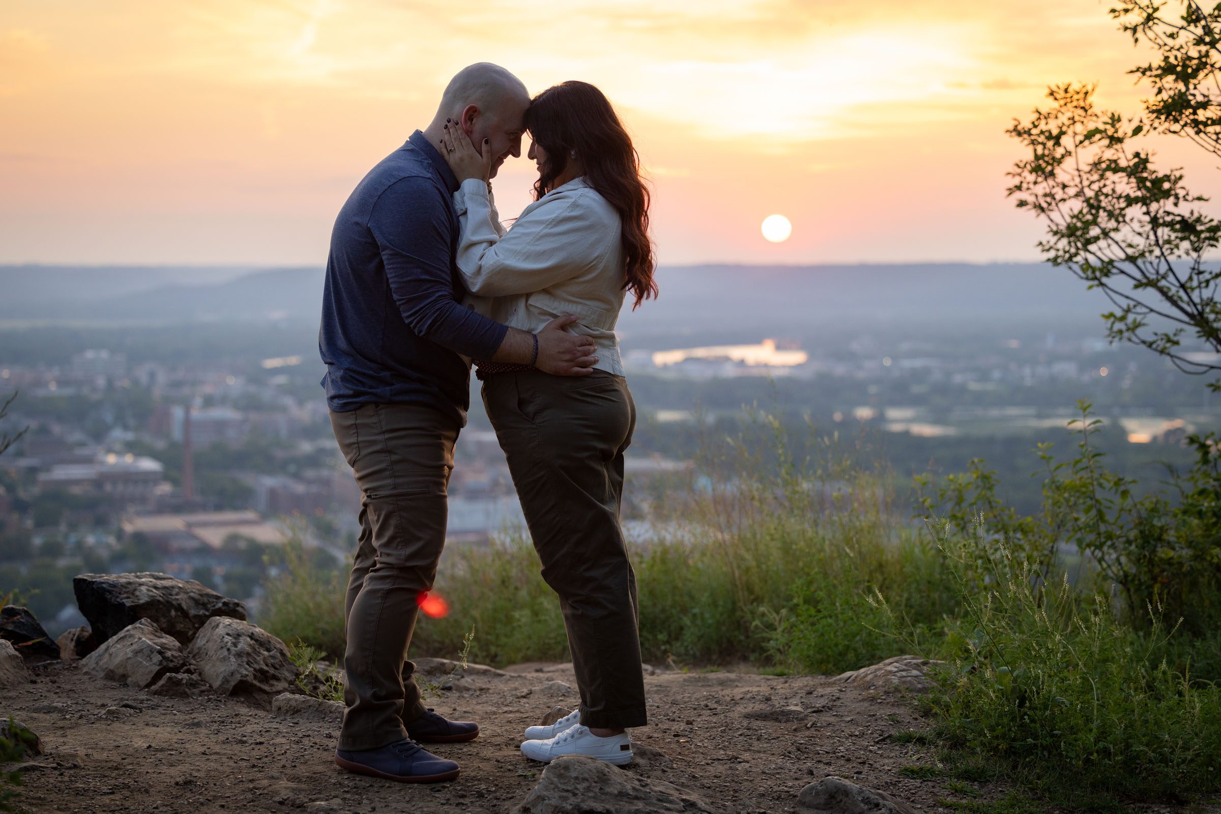 Engaged couple hugging at sunset.